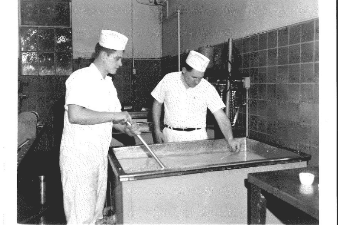 Professor Ernstrom (right) teaches student (left) who is stirring a creamery product