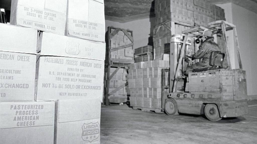 Forklift moving a large stack of government purchased cheese
